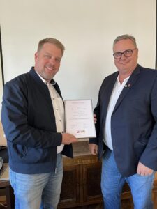 Zwei Männer bei der Übergabe einer Ehrenurkunde für langjähriges Engagement im Handwerk, Auszeichnung mit der silbernen Ehrennadel.
