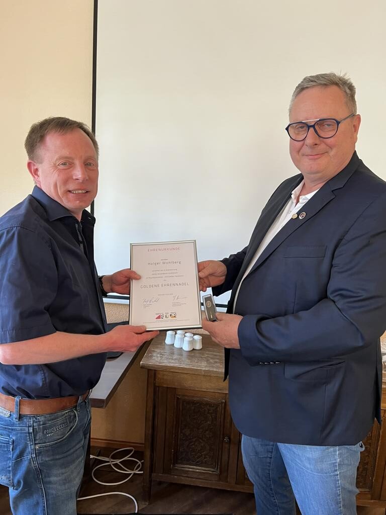 Zwei Männer bei feierlicher Übergabe einer Ehrenurkunde und goldenen Ehrennadel für langjähriges Engagement im Handwerk