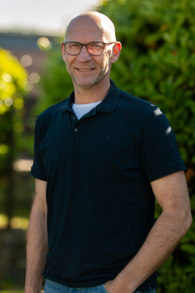 Mann mit Brille und dunkelblauem Poloshirt im Grünen, Mitglied der Tischler-Innung Stade