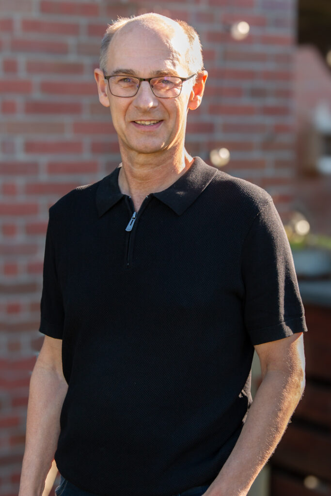 Mann mit Brille und schwarzem Poloshirt vor Backsteinwand, Mitglied der Fliesen- und Natursteinleger-Innung Stade