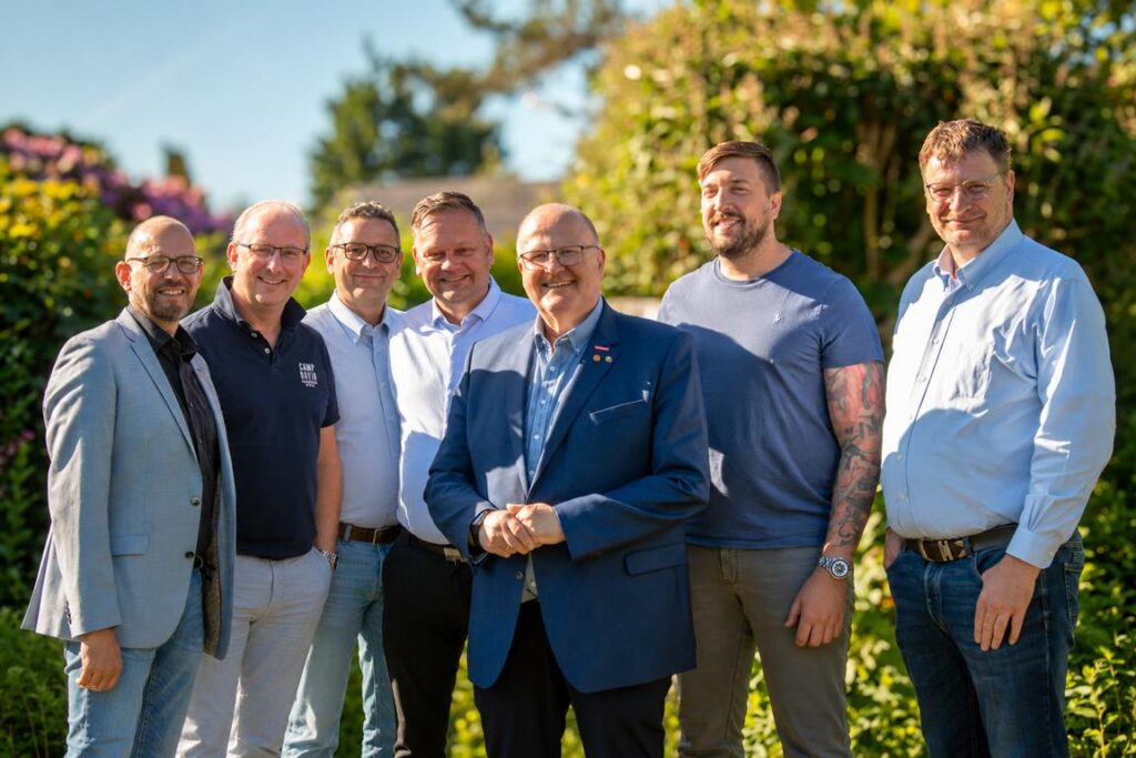 Gruppenfoto des Teams der Kreishandwerkerschaft Stade im Freien vor grüner Natur, sieben Männer lächeln in die Kamera